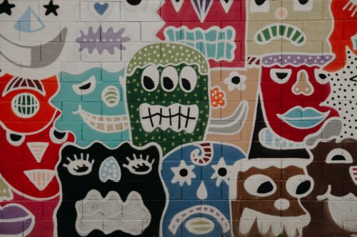 Close-up of a mural with a bunch of abstract faces in different colors.