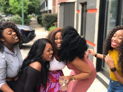 A group of friends laughing together on a sidewalk.