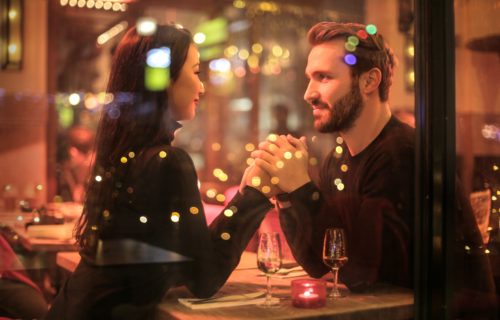 A couple sits at a table in a restaurant holding hands.