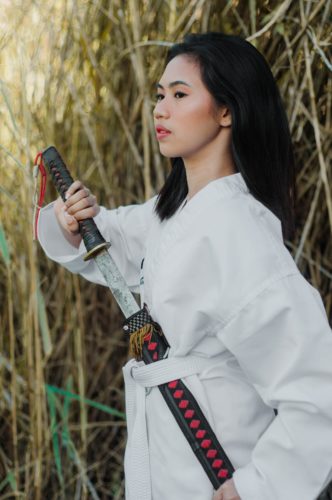 A person wearing a gi and pulling a sword from its sheath.