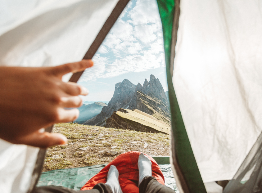 a person looking out a tent door to see a mountain.