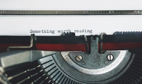 Close-up of a typewriter with the words "Something worth reading" typed onto a sheet of paper.