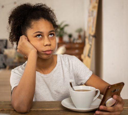 Teenager holds her phone and rolls her eyes.