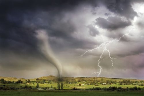A tornado touches down in a rural town as lightning strikes nearby.