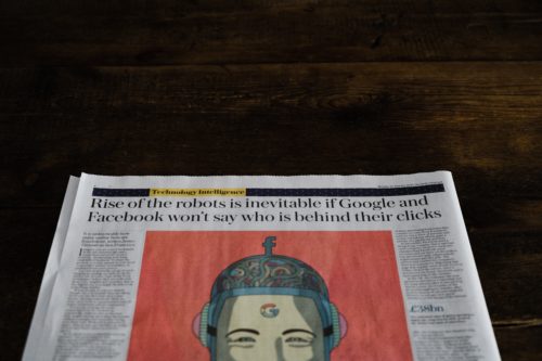 A newspaper with an image of a face and the headline: "Rise of the robots is inevitable if Google and Facebook won't say who is behind their clicks."