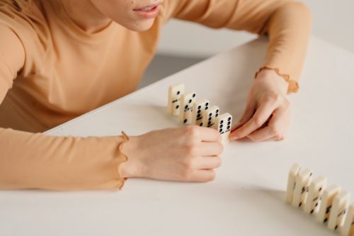 A person setting up a line of dominoes on a tabletop.