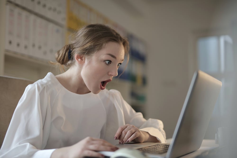 A person looks at a computer screen with a shocked expression.