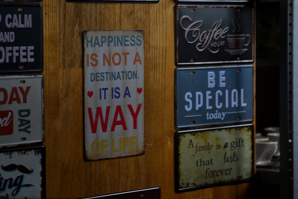 A theme on a colorful tin sign: "Happiness is not a destination. It is a way of life."