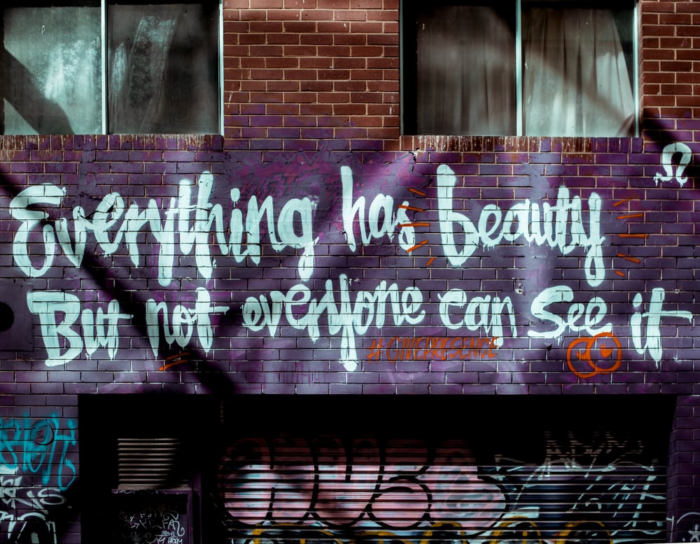 A theme spray painted on a brick wall: "Everything has beauty but not everyone can see it."