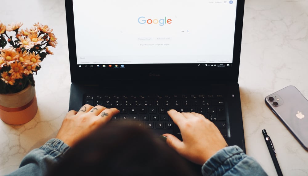 A person's hands on the keyboard of a laptop with a Google search screen open for researching historical fiction.