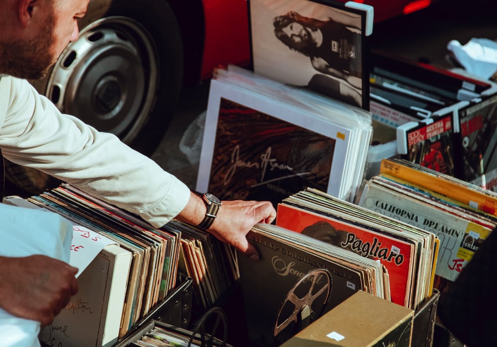 A hand looks through vintage record albums.