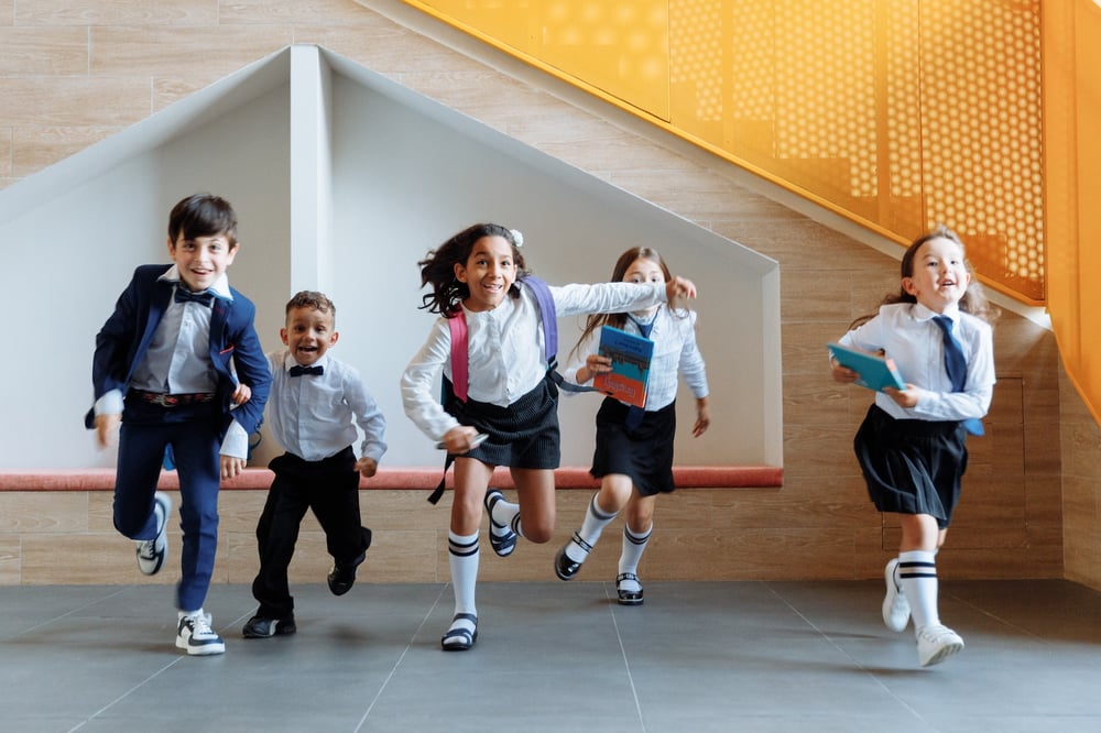 Kids in school uniforms running down a hallway.