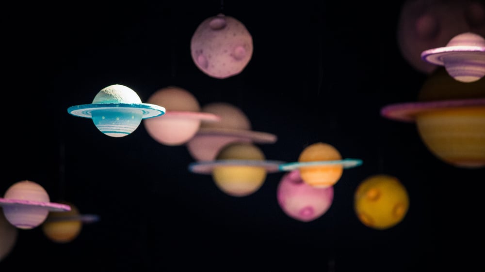 Small, handmade planets dangle against a black background.