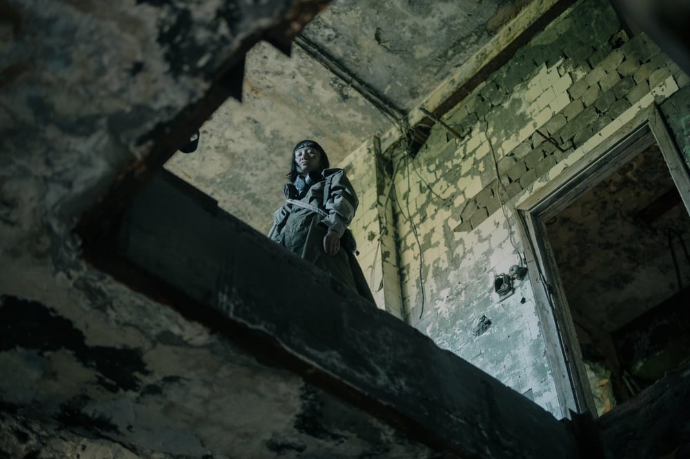 A person looks down from the upper level of an abandoned building.