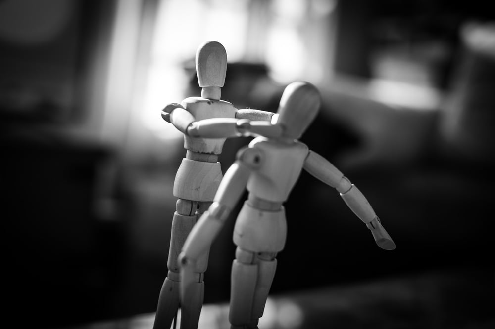 Two wooden drawing mannequins are posed as if one is strangling the other.