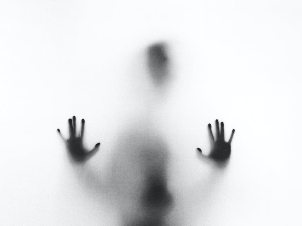 Ghostly hands press against a foggy wall.