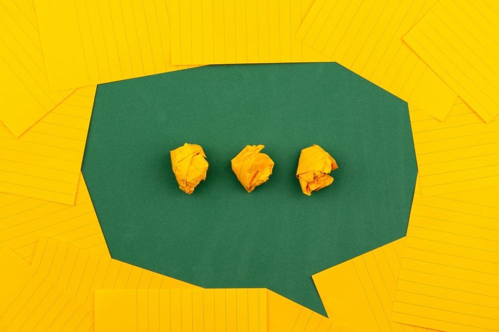 A green speech bubble with balls of yellow crumpled paper forming ellipses.