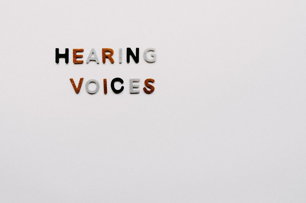 The phrase "hearing voices" in multicolored letters on a white background. 