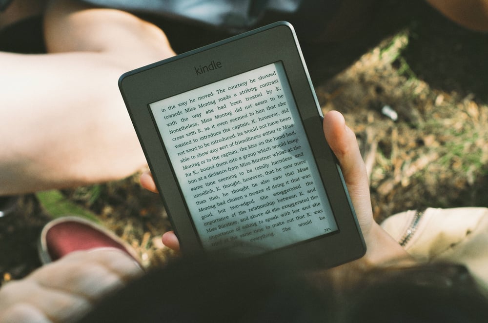 A hand holding a Kindle e-reader.