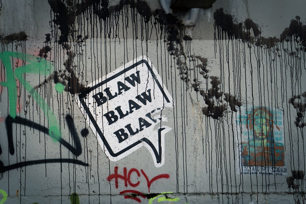 A wall covered in graffiti, including a dialogue bubble that reads, "Blaw Blaw Blaw."