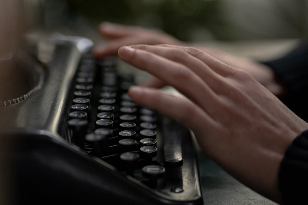 A close up of hands typing on a typewriter.
