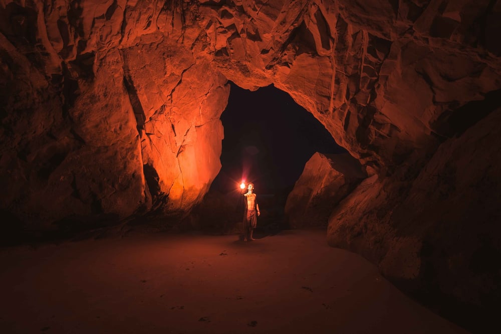 An adventurer holding a flashlight in a dark cave.
