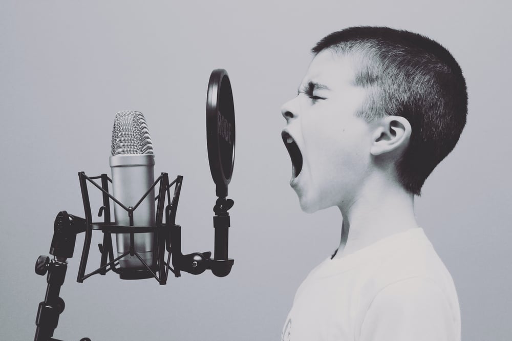 Black and white image of a child yelling into a microphone.