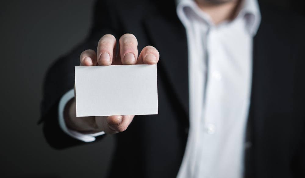 Close up of a person's hand holding out a blank business card.