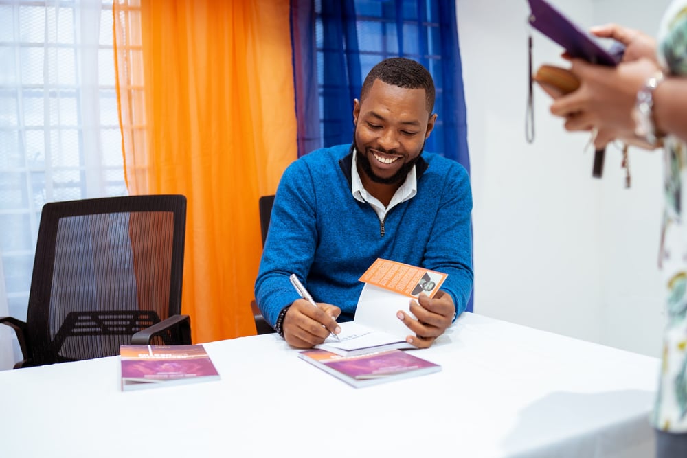 A smiling author signs a book for a fan.