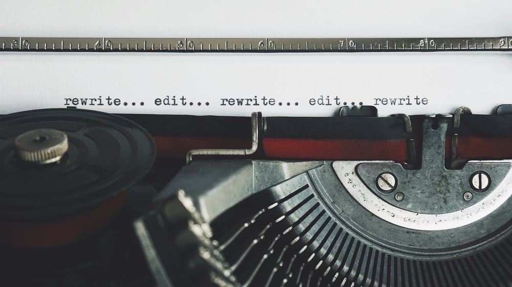 Close-up of an old manual typewriter typing the words "rewrite... edit... rewrite... edit... rewrite."
