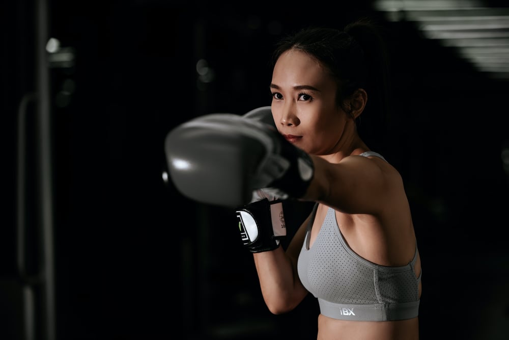 A female-presenting boxer punches toward the camera.