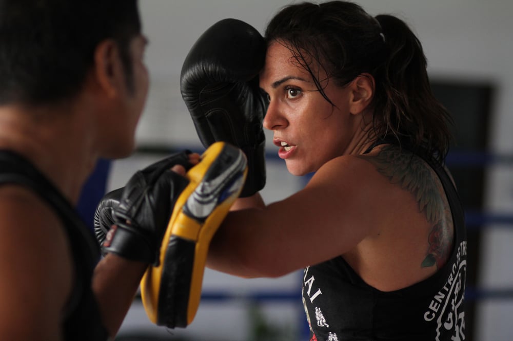 A male-presenting boxer and female-presenting boxer engaged in a match.