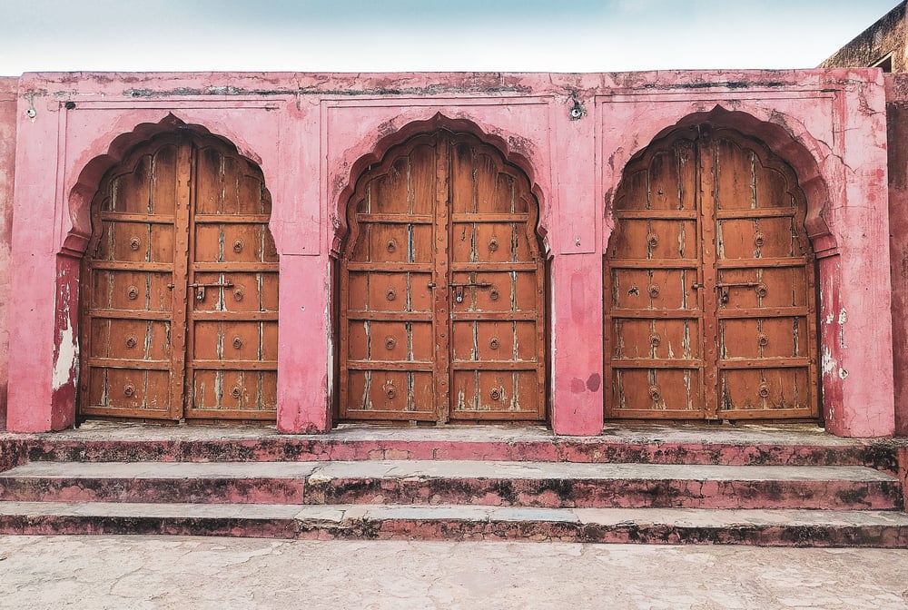 Three wooden doors in an old red stone building, symbolizing the three publishing processes.