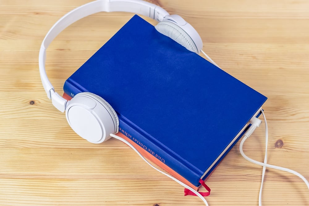 White headphones fitted over a blue book.