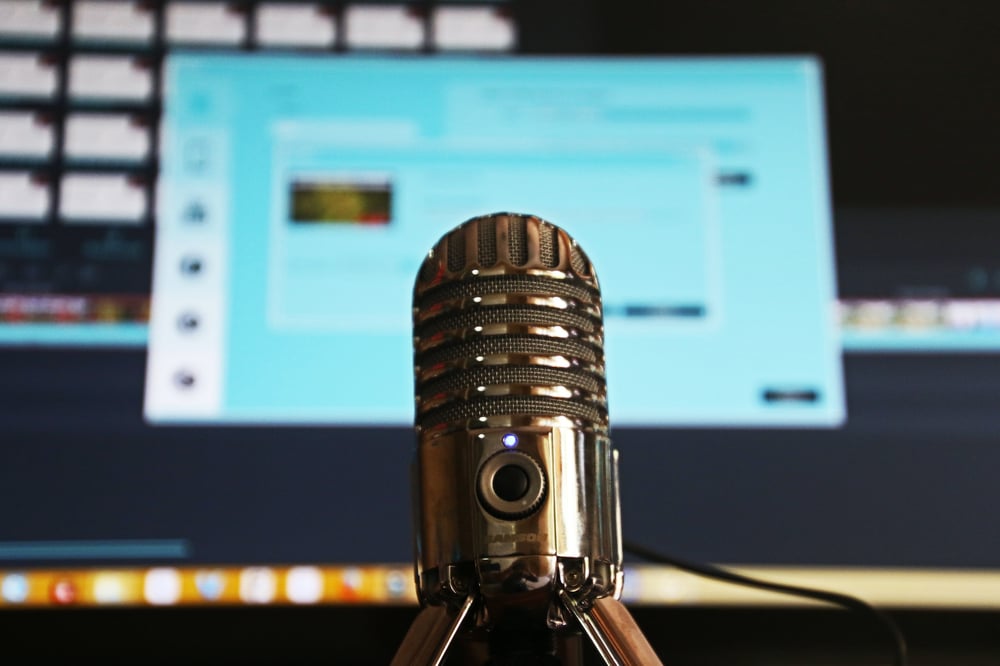 A microphone with an open and blurred computer screen in the background.