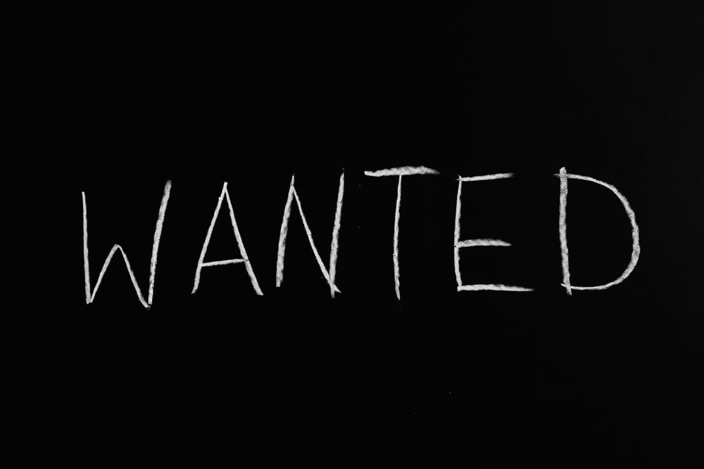 A black sign with the word "WANTED" written in white chalk.