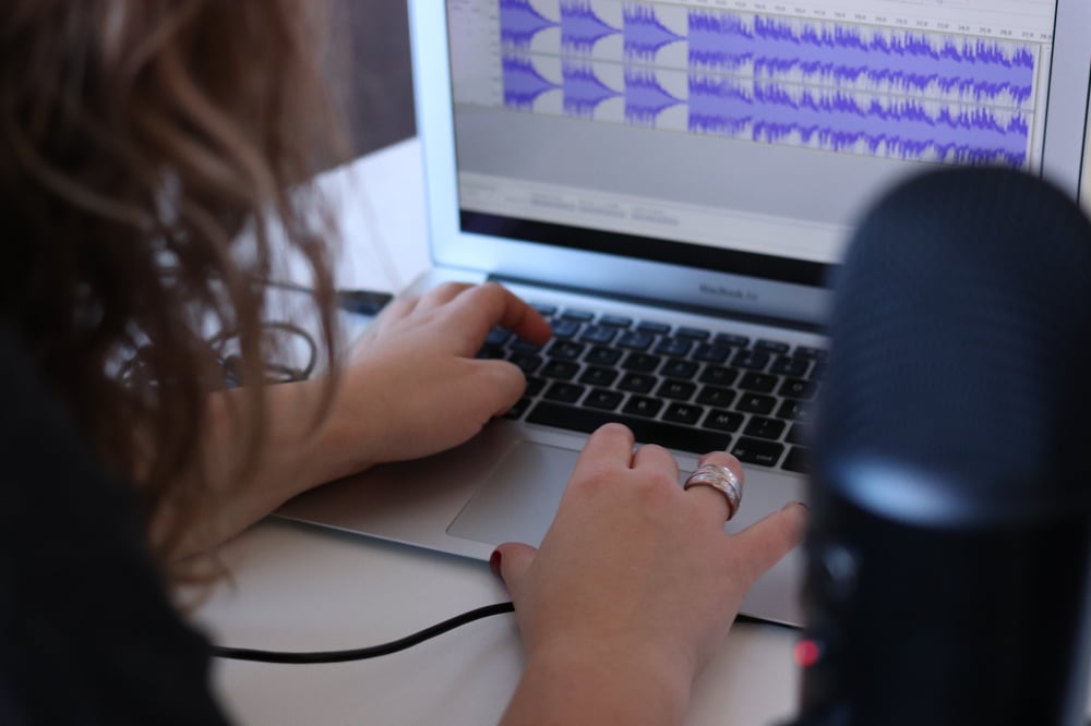 A person's hands on a laptop, editing an audio recording.