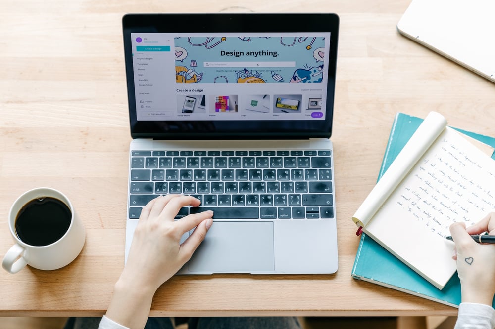 Hands working on a laptop that's open to a cover design tool.