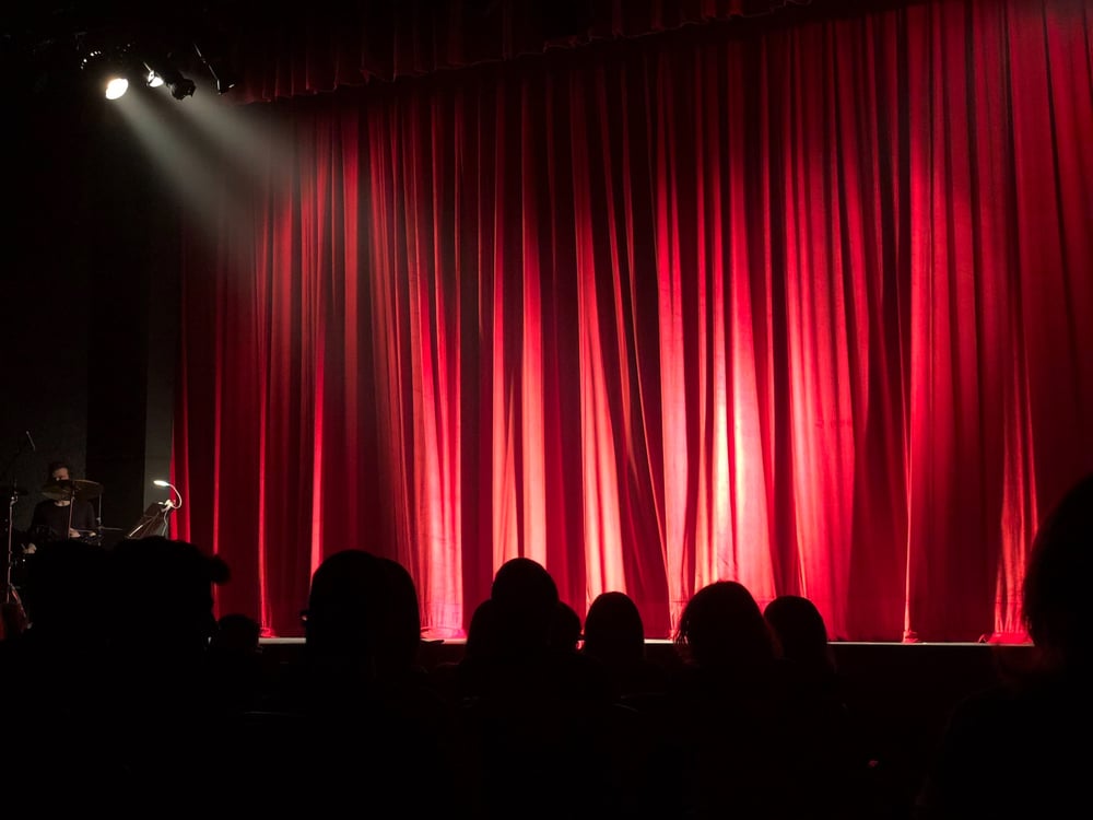 A spotlight shines on a red stage curtain.