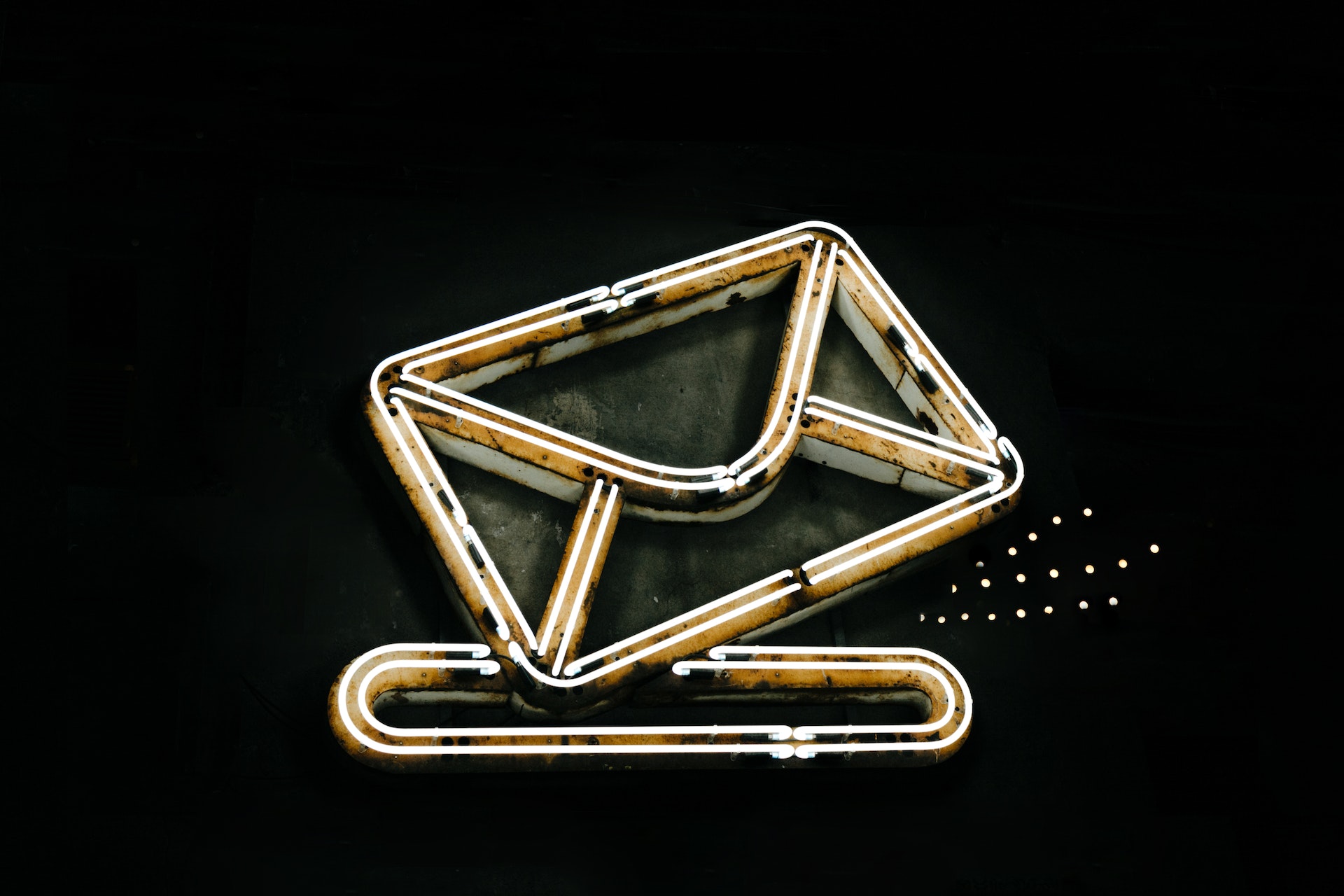 A neon light shaped like an envelope going into a mail slot.
