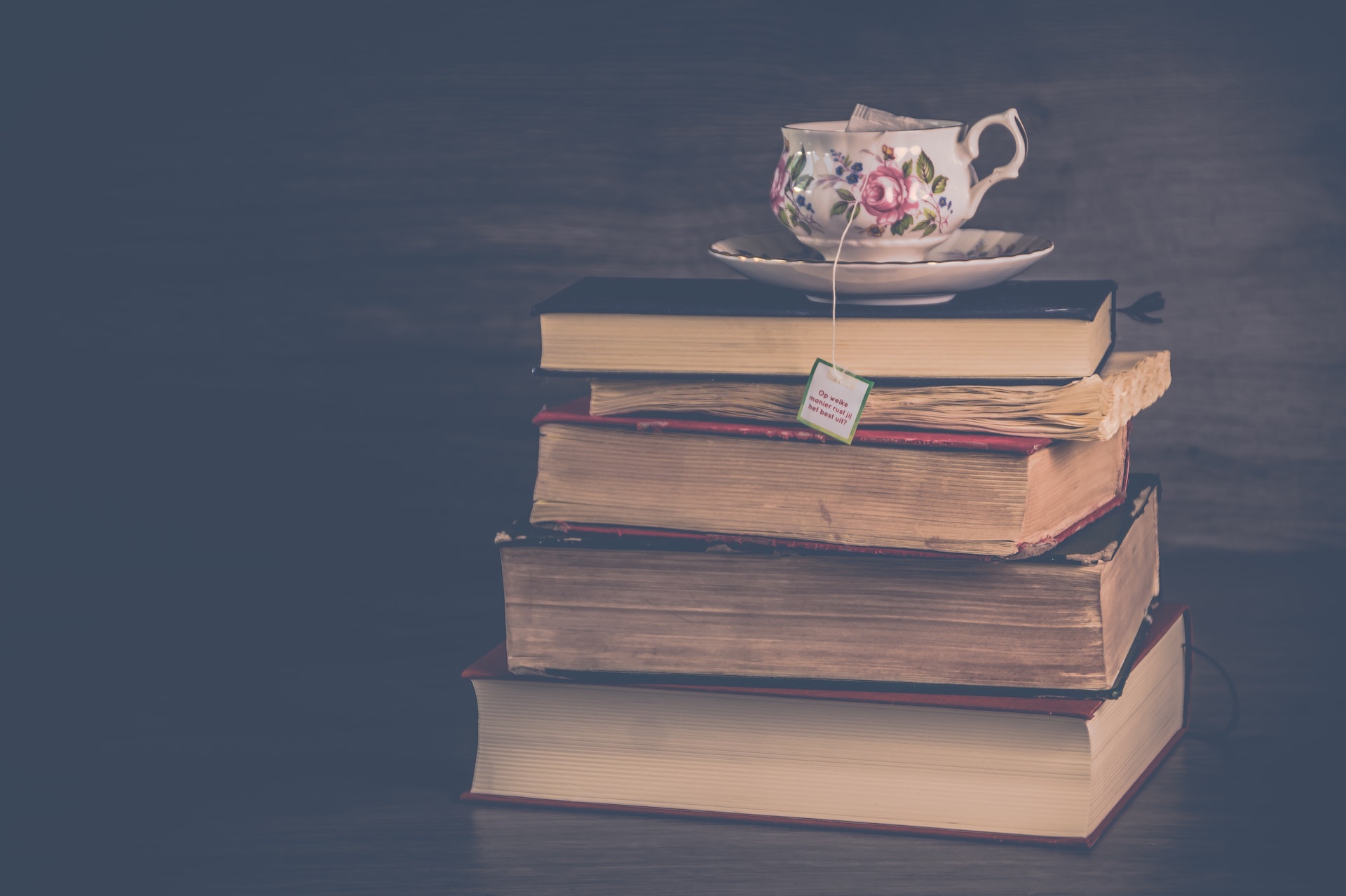 A stack of books with a cup of tea on top.