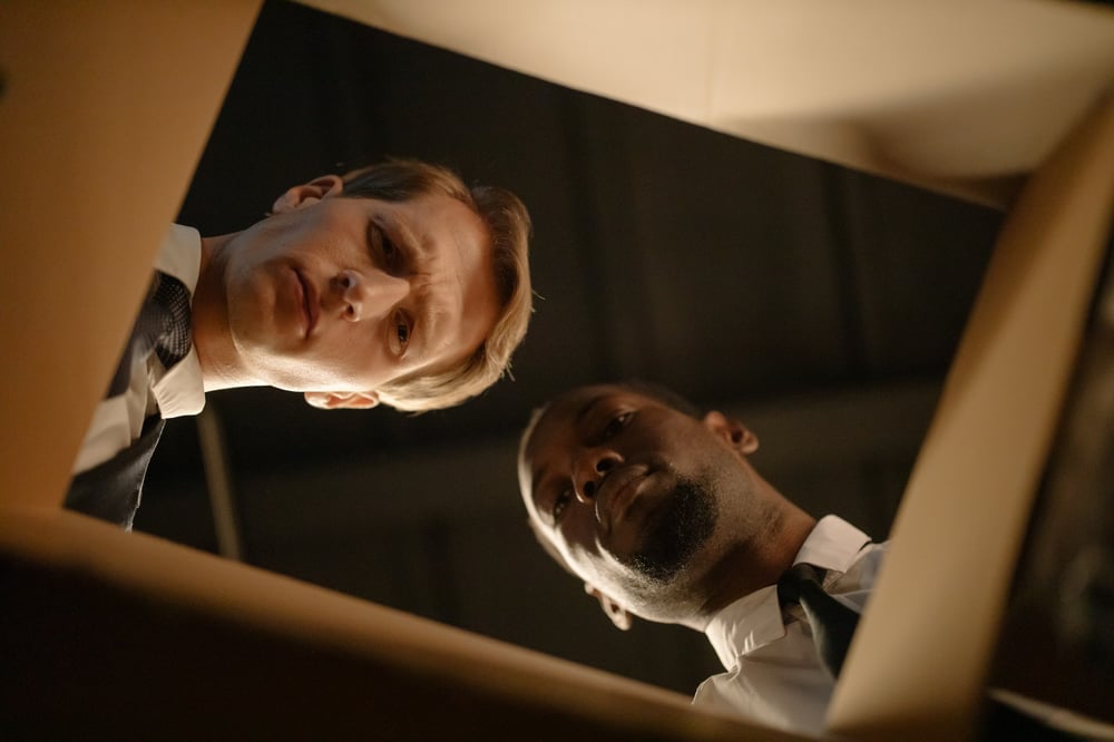 View from the bottom of a box showing two detectives looking down into the box.