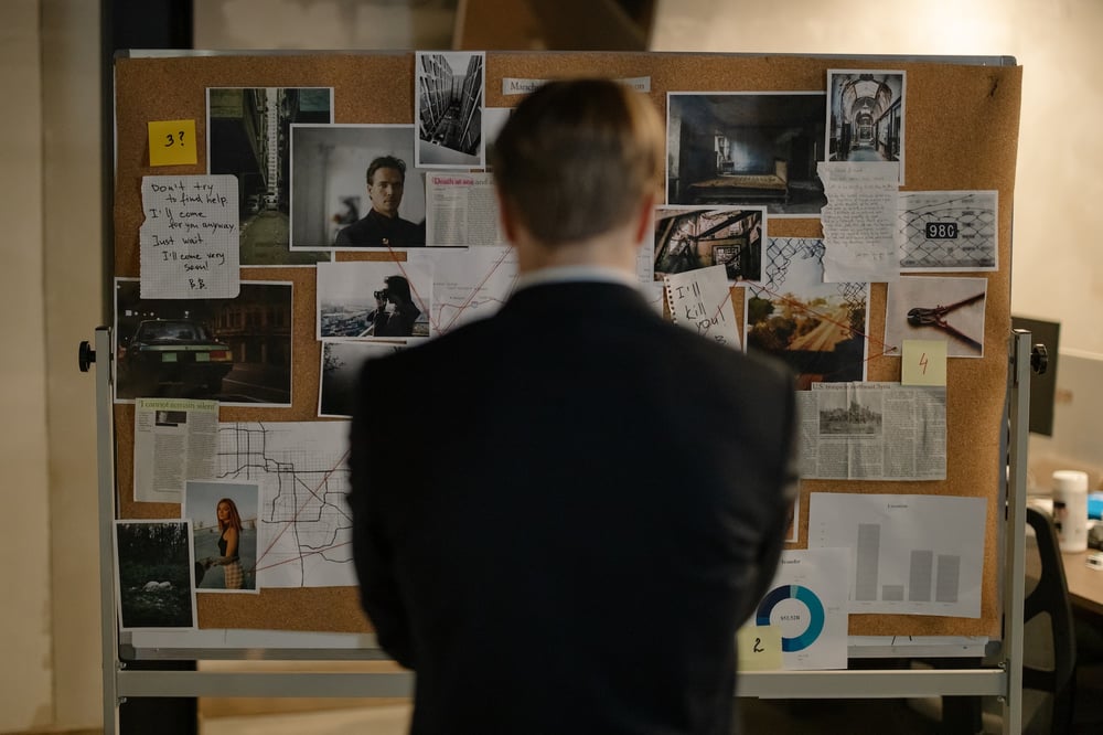 A detective looks at an evidence board.