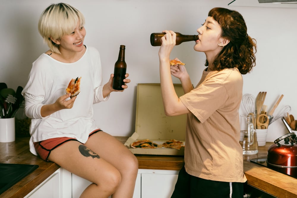 A couple eats pizza in a small apartment kitchen.