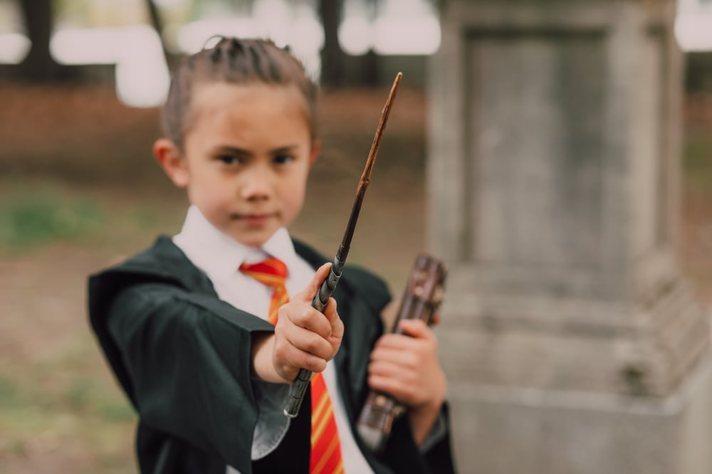 A child holds a wand as if casting a spell.