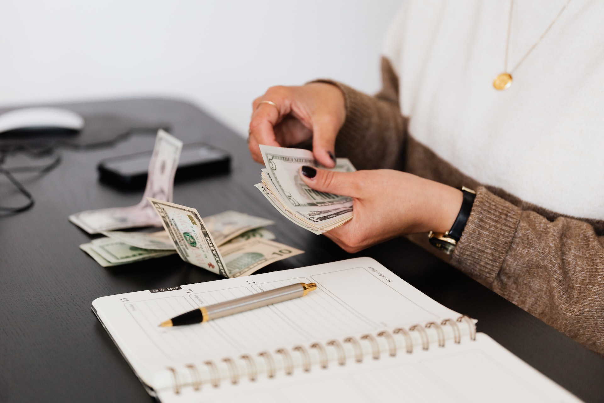 Hands count money on a desk.