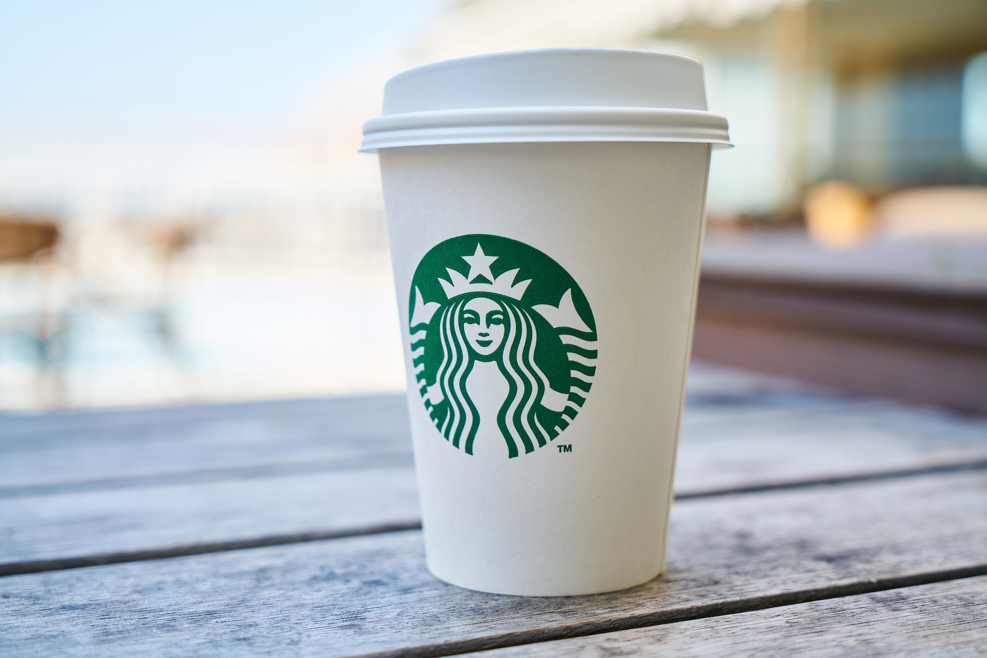 A Starbucks coffee cup sits on a cafe table.