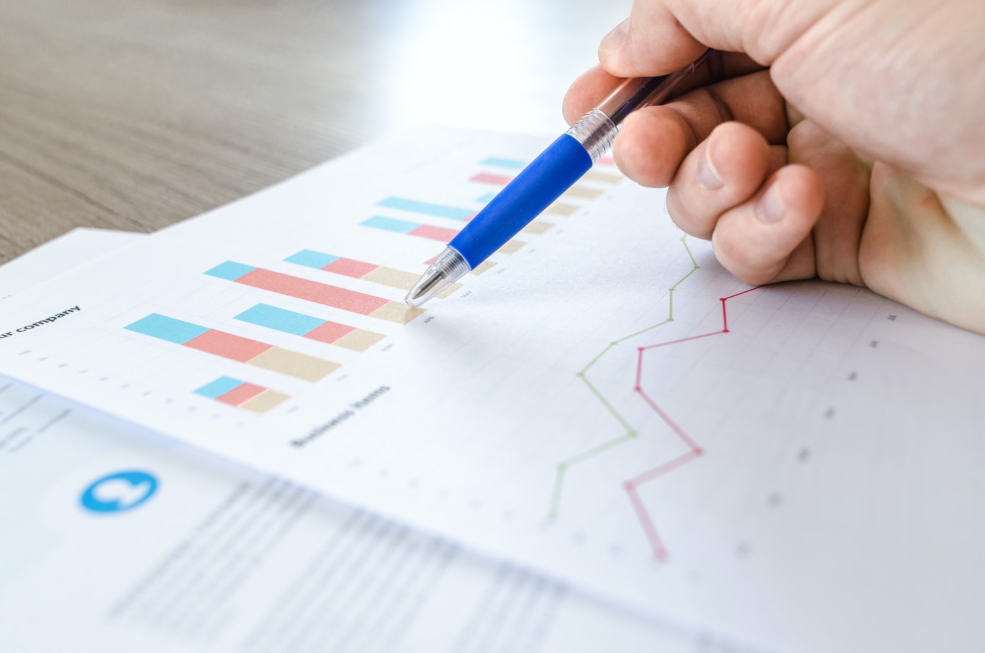 Using a pen, a hand points to a bar graph on a piece of paper.