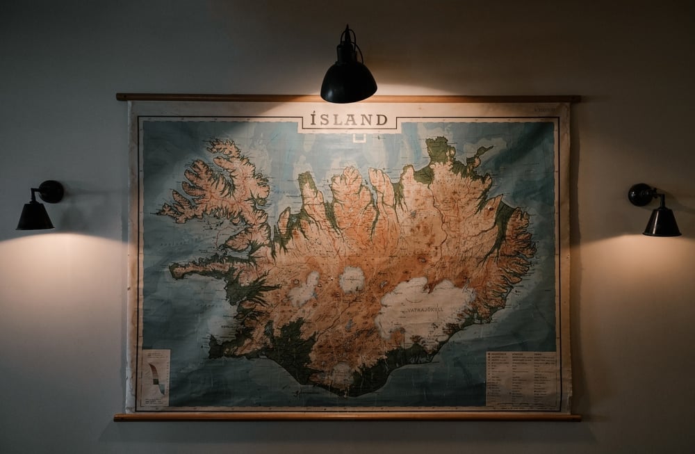 Three lights shine on a giant, old wall map.
