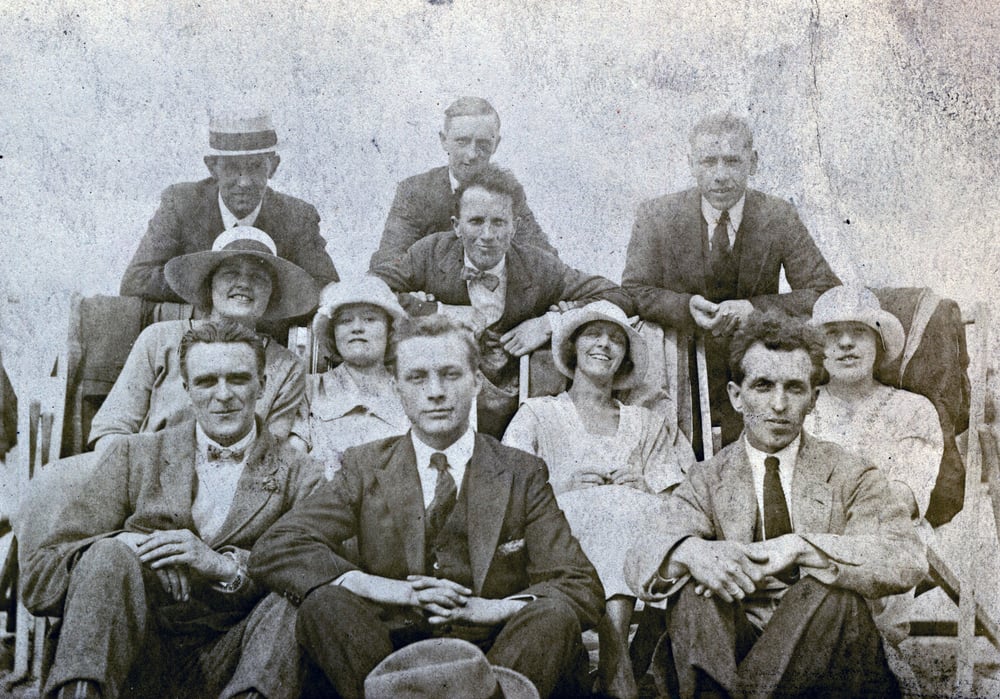 An old black-and-white photograph of several happy looking adults.